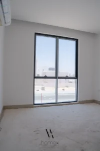 نوافذ ألمنيوم داكنة على كتلة بيضاء لفيلا حديثة في أبوظبي