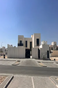 واجهة فيلا سكنية حديثة في أبوظبي بكتل هندسية بيضاء وإطارات ألمنيوم داكنة من تصميم بيت الخبرة