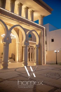 المدخل الخارجي لفيلا فاخرة بأبوظبي مع أعمدة كلاسيكية وأقواس وإضاءة ليلية